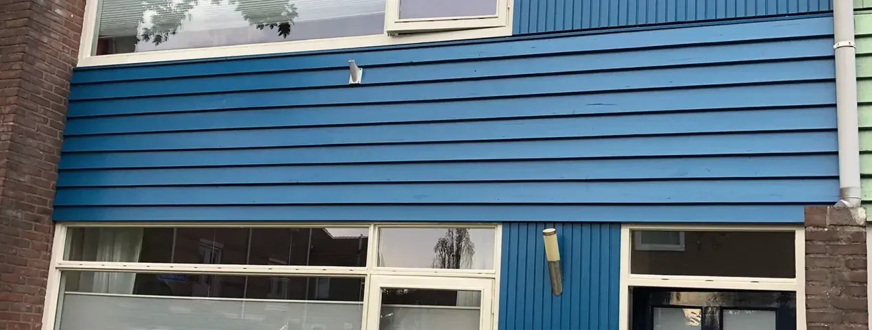 Blauw geschilderde houten gevel van een tussenwoning.
