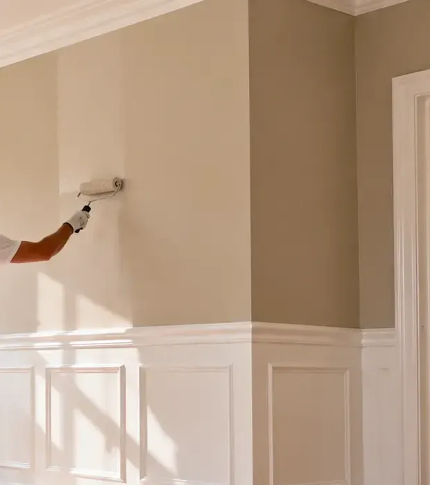 Een binnenmuur wordt met een roller gesausd; de vers gerolde baan is lichter dan de rest van de muur.